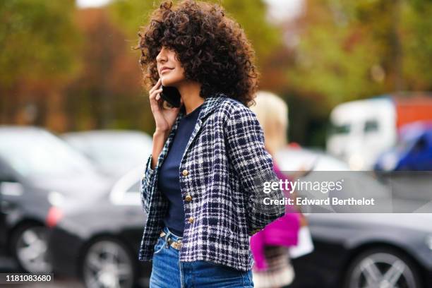 Guest wears a navy blue top, a black and white checkered Chanel jacket, blue denim pants, outside Chanel, during Paris Fashion Week - Womenswear...