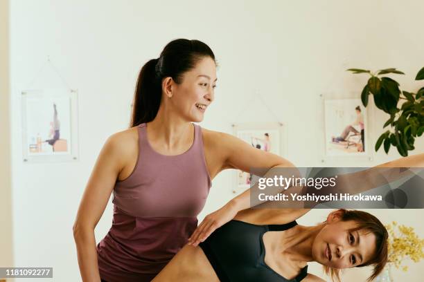 mature male woman pilates instructor leading class on pilates reformers in fitness studi - happy male side view stock-fotos und bilder