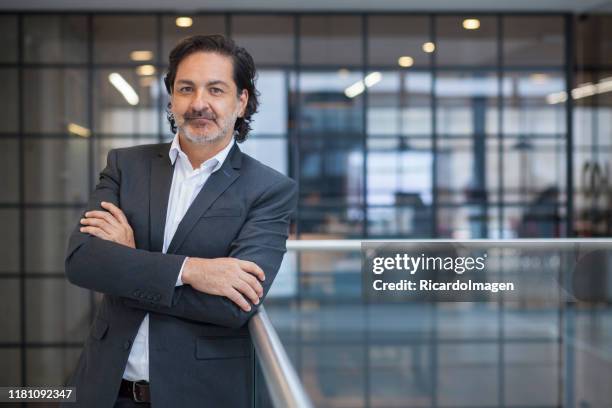 senior executive latin man met blauw pak en gekruiste armen - colombian ethnicity stockfoto's en -beelden