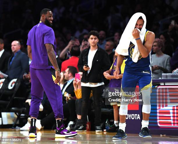 LeBron James of the Los Angeles Lakers and Stephen Curry of the Golden State Warriors laugh on the sidelines during a timeout in a 104-98 Lakers...