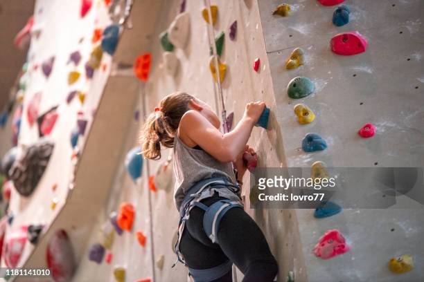 adolescente chica escalando en la pared de escalada - alpinismo fotografías e imágenes de stock