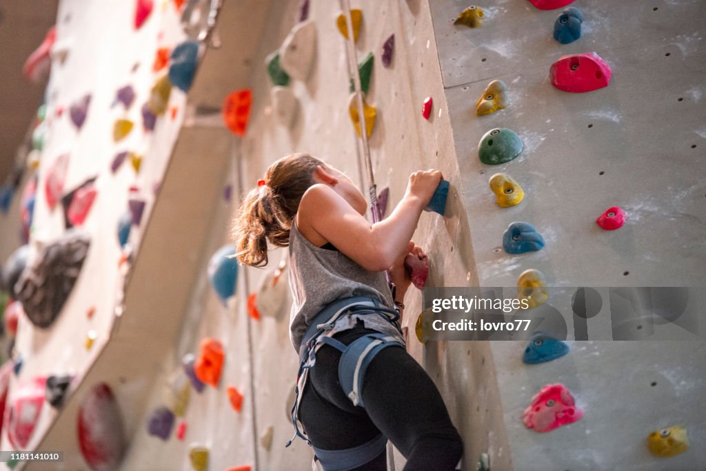 Teenage girl climbing on climbing wall