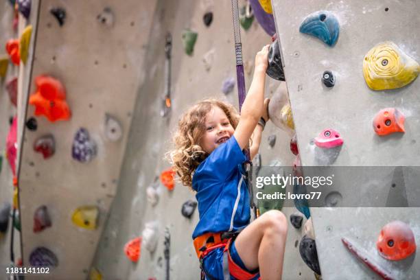 boy climbing on climbing wall - climbing wall stock pictures, royalty-free photos & images