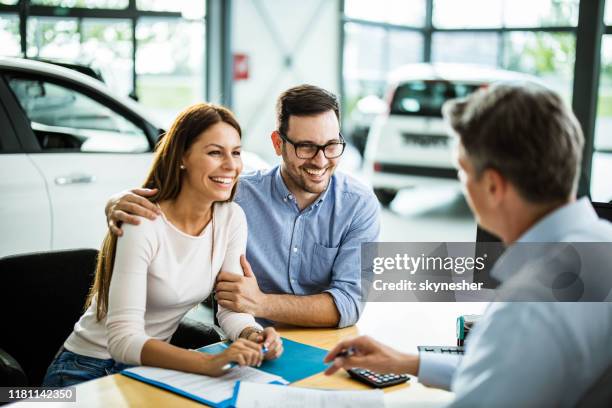 幸福的夫婦在汽車陳列室與銷售人員交談。 - buying a car 個照片及圖片檔
