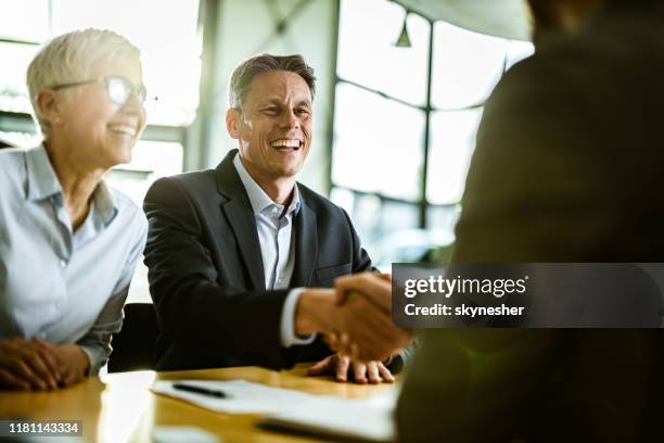 happy business couple came to an agreement with their agent in the office. - bankers stock pictures, royalty-free photos & images