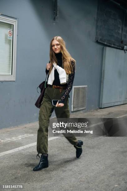 Model Natalie Ogg wears a black lace top, white sweatshirt tied across her chest, green military-style pants, and black booties after the Off-White...