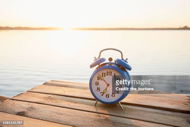 retro alarm clock on jetty at lake early in the morning during sunrise - alarm clock close up stock pictures, royalty-free photos & images
