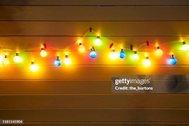 illuminated colorful string lights for party decoration at a yellow painted wooden wall in the evening - led lampe photos et images de collection