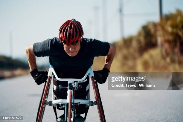 Senior athlete in a racing wheelchair practicing on a rural road.