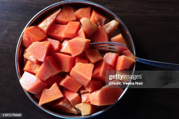 chopped papaya fruit in a plate on a wooden table - papaya stock pictures, royalty-free photos & images