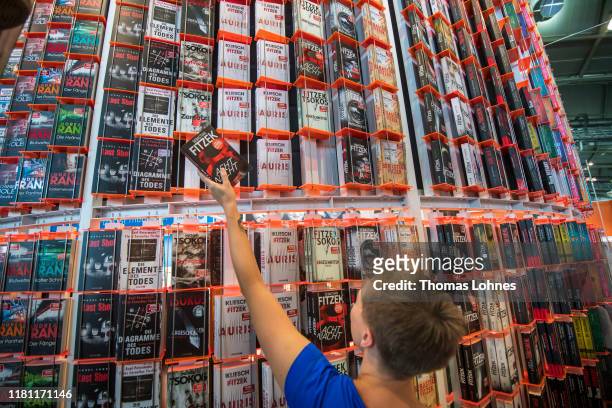 An employee poses with a book as she prepares the stand of Droemer at the Frankfurt Book Fair on October 15, 2019 in Frankfurt am Main, Germany. The...