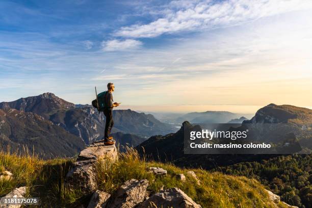 hiker alone looking at view from mountain top - vetta foto e immagini stock