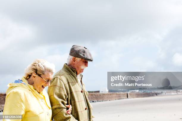 retired couple walking on beach - jersey england stock pictures, royalty-free photos & images