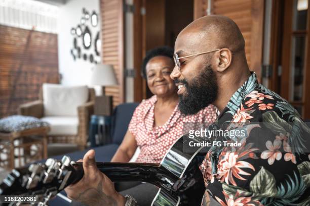 uomo felice che suona la chitarra con sua madre - arts culture and entertainment foto e immagini stock
