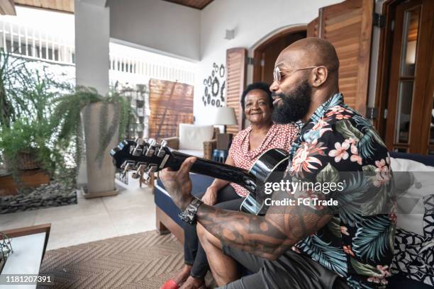 happy man playing guitar to his mother - black guitarist stock pictures, royalty-free photos & images