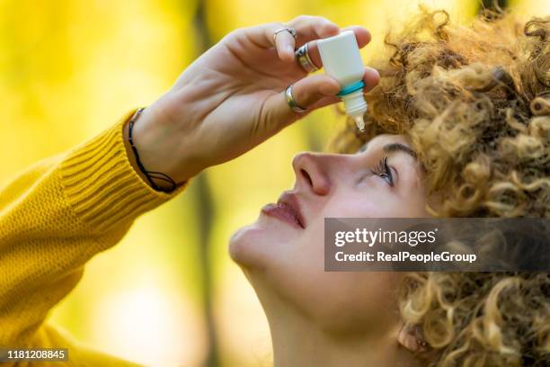 young woman putting eye drops - colírio imagens e fotografias de stock