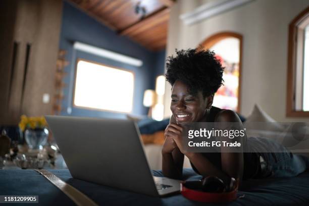 young women watching movie on a laptop at home - mood stream stock pictures, royalty-free photos & images