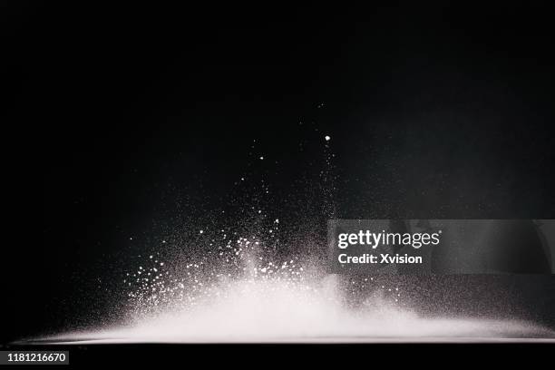 flour dancing in high speed with black background - schnee pusten stock-fotos und bilder
