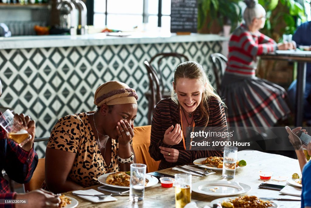 Female colleagues laughing during business lunch