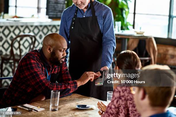 businessman paying for lunch using card payment machine - restaurant bill stock pictures, royalty-free photos & images