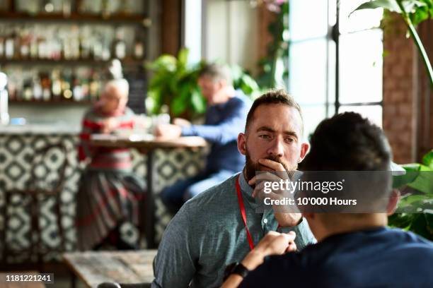 man listening thoughtfully to business colleague in restaurant - amigos hombres en restaurant fotografías e imágenes de stock