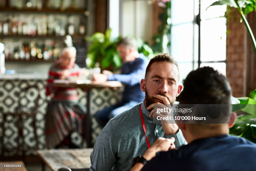 Man listening thoughtfully to business colleague in restaurant