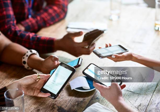 friends splitting bill using contactless payment on smartphones - paying with mobile stock pictures, royalty-free photos & images