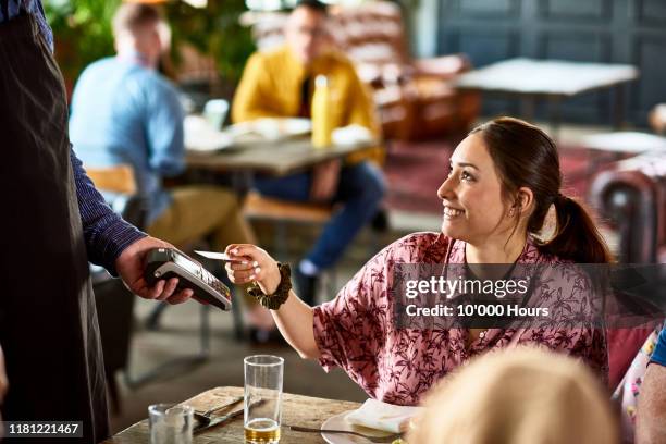 attractive woman using contactless technology in cafe - pay with credit card stockfoto's en -beelden