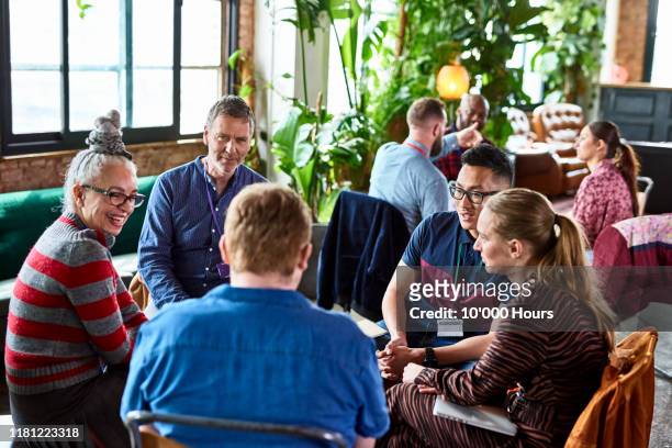 diverse colleagues meeting in open office space - teambuilding stockfoto's en -beelden
