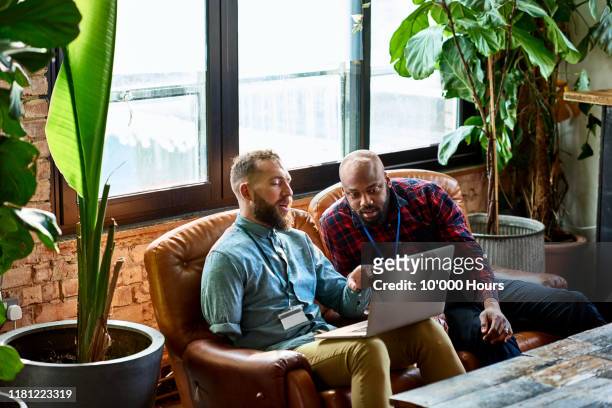 man using laptop in cafe with business colleague - physical disability stock pictures, royalty-free photos & images