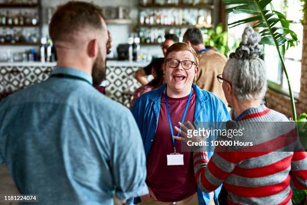 young man laughing and enjoying after work drinks - persons with disabilities stock-fotos und bilder