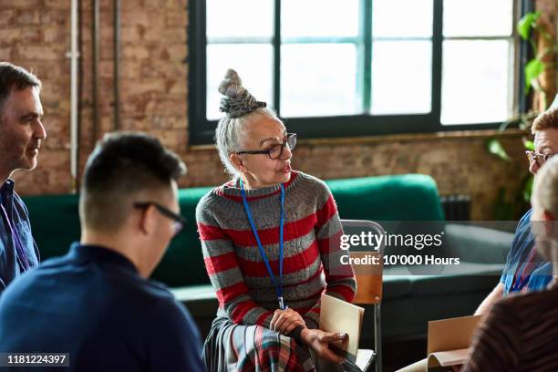 senior woman talking to small group in office training session - inclusive leadership stock pictures, royalty-free photos & images