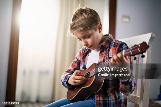 ragazzino che suona la chitarra a casa - ukulele foto e immagini stock