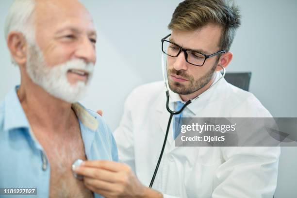 arts die het hart van de senior man onderzoekt met stethoscoop. - long beard stockfoto's en -beelden