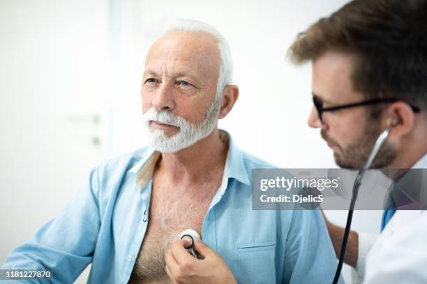 l'anziano ha il cuore esaminato con stetoscopio in ospedale. - listening to heartbeat foto e immagini stock