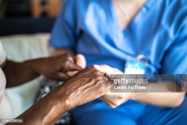 close-up of home caregiver and senior woman holding hands - demência imagens e fotografias de stock