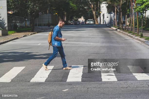 young man walking at crosswalk on a sao paulo's street - pedestrian crossing man stock pictures, royalty-free photos & images