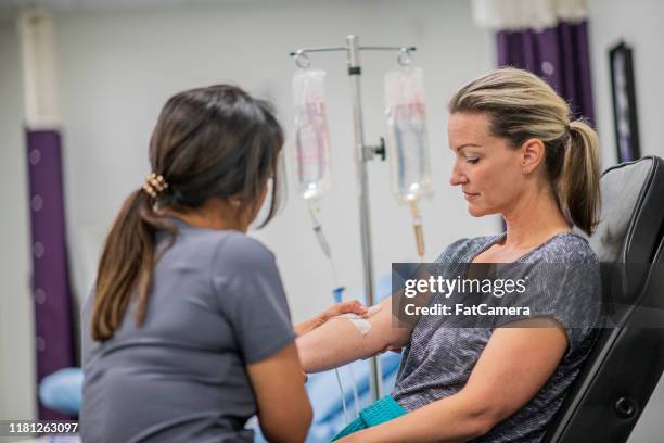 verpleegster geven iv drip behandeling aan patiënt stockfoto - infuus stockfoto's en -beelden