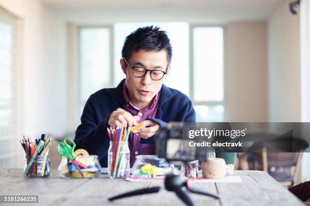 man filming an arts and crafts tutorial - origami instructions stock pictures, royalty-free photos & images