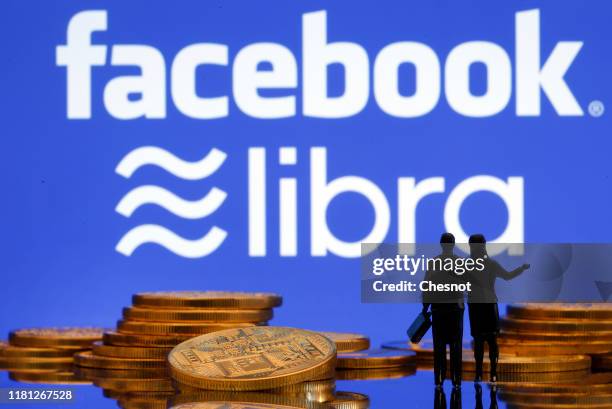 In this photo illustration, a visual representation of digital cryptocurrency coins sit on display in front of Libra and Facebook logos on October...