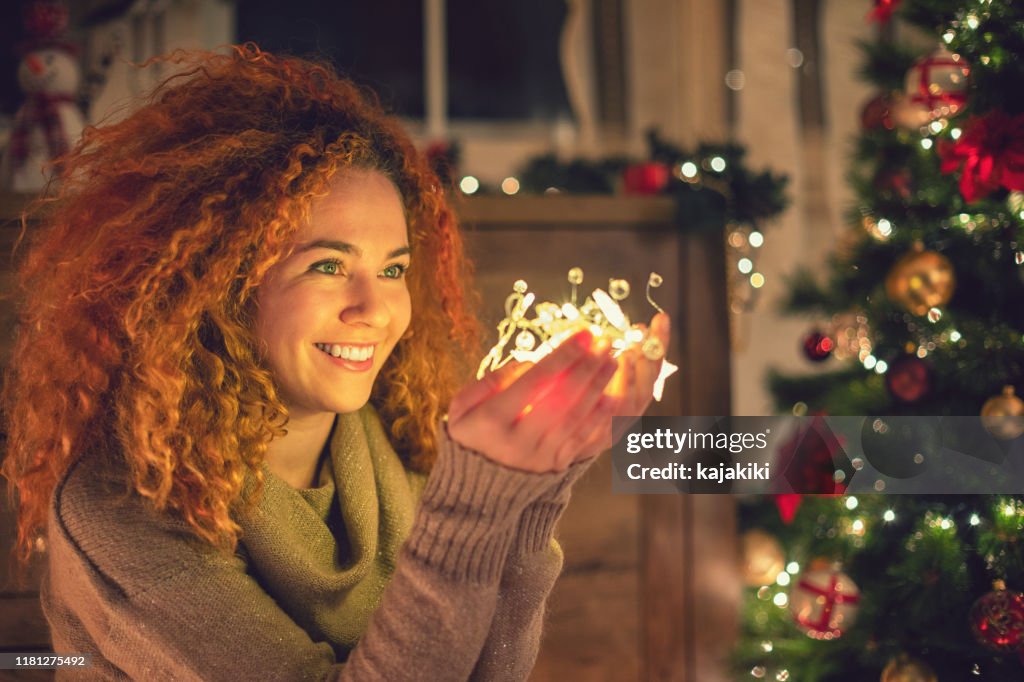 Schöne Mädchen hält glänzende Weihnachtsbeleuchtung