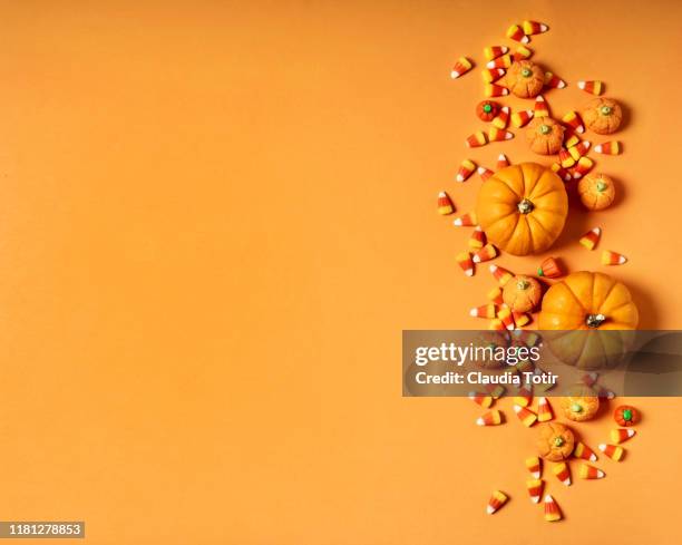 candy corn and pumpkins on orange background - gominola en forma de maíz fotografías e imágenes de stock