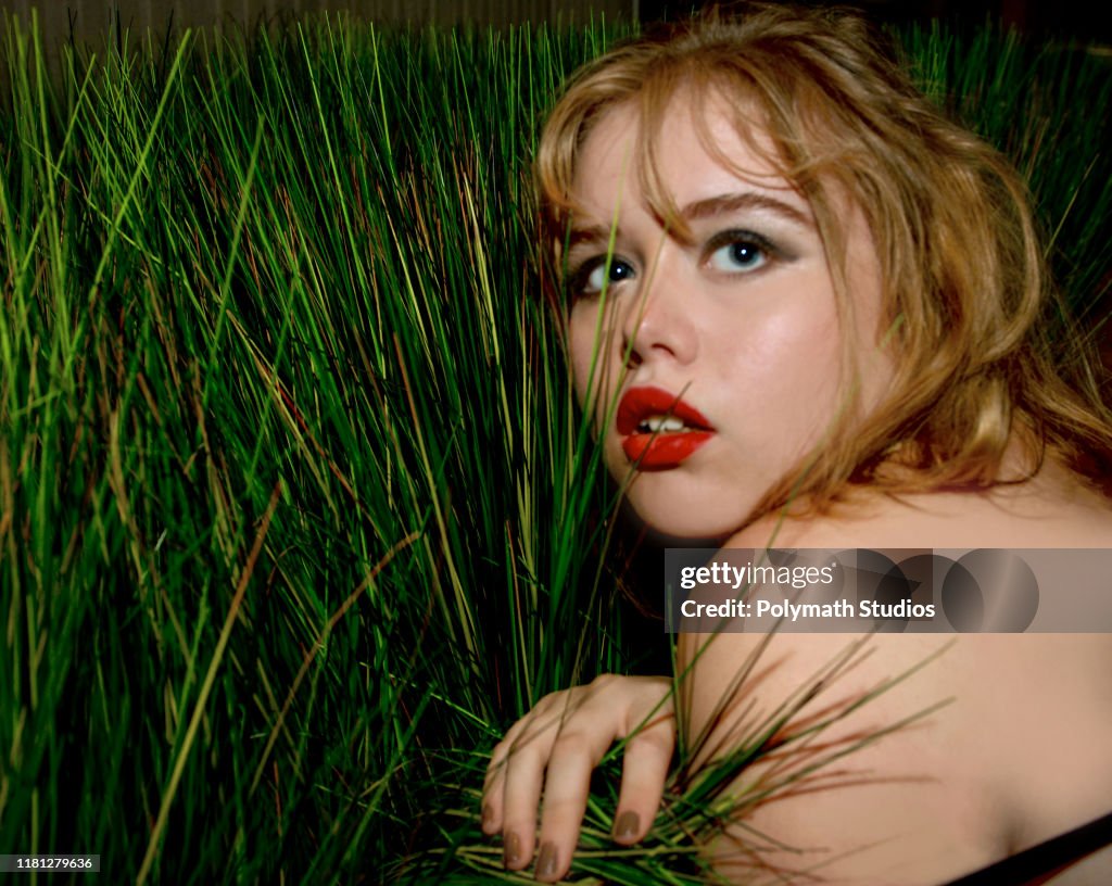 Dewy red lipped girl rests in foliage