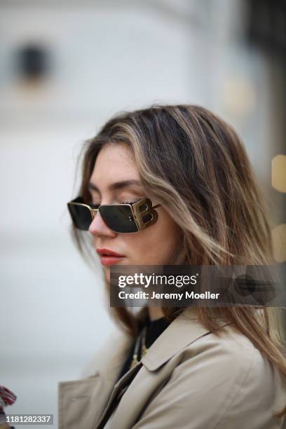 Milena Karl wearing Zara boots, Burberry sunglasses, Burberry skirt and trenchcoat, Mango shirt and Prada bag on October 14, 2019 in Hamburg, Germany.