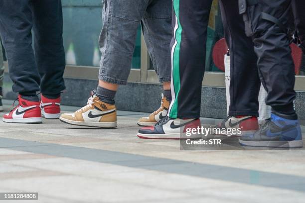 This photo taken on October 26, 2019 shows people wearing Nike sneakers queueing outside a Nike store to buy the newly-released Nike sneaker in...