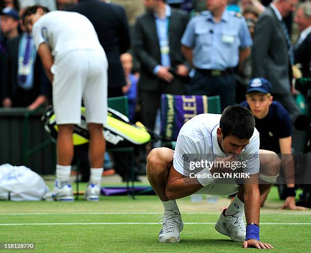 Serbian player Novak Djokovic eats the grass after beating Spanish player Rafael in the men's single final at the Wimbledon Tennis Championships at...