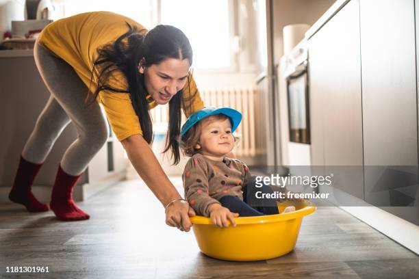 young mother with a baby girl doing housework and having fun - cleaning kitchen stock pictures, royalty-free photos & images