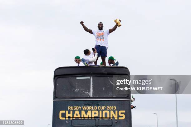 South African Rugby captain Siya Kolisi holds up the Web Ellis Trophy as the South African Rugby World Cup winner team parades on an open top bus...