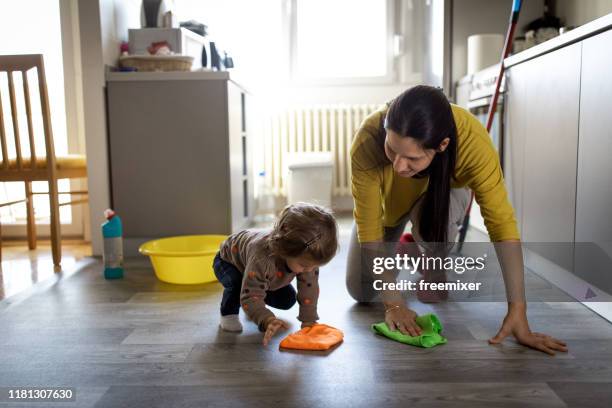 young mother with a baby girl doing housework - kitchen mop stock pictures, royalty-free photos & images