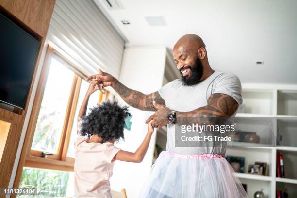 funny father with tutu skirts dancing like ballerinas - father stock pictures, royalty-free photos & images